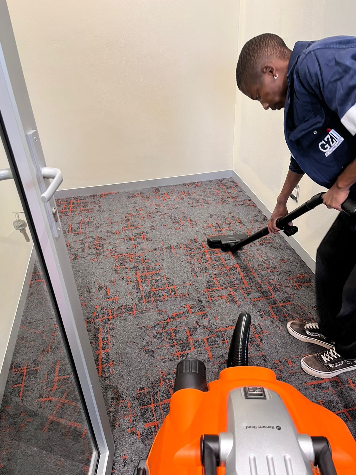 Worker vacuuming a grey patterned office carpet